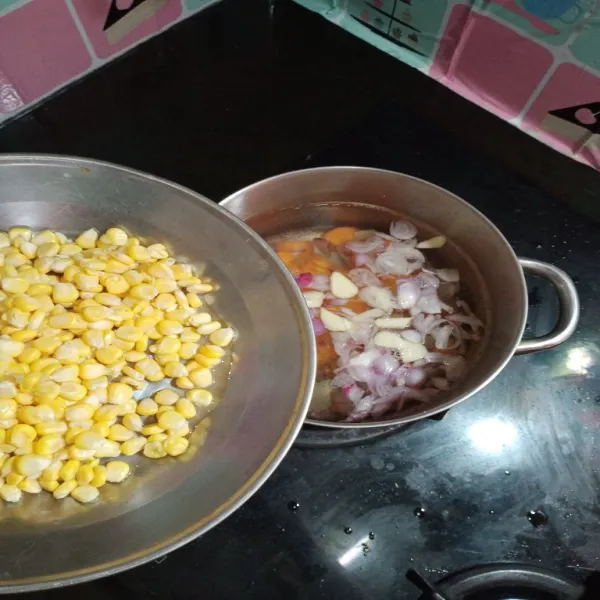 didihkan air dalam panci, kemudian masukan kedua bawang, laos, jagung dan wortel nya, masak hingga agak lunak