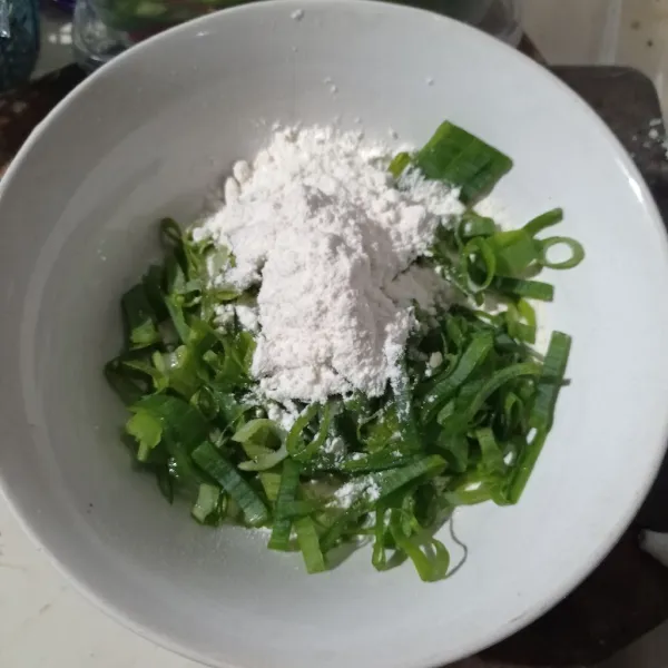 Masukan tepung serbaguna, tepung terigu, dan daun bawang kedalam wadah.