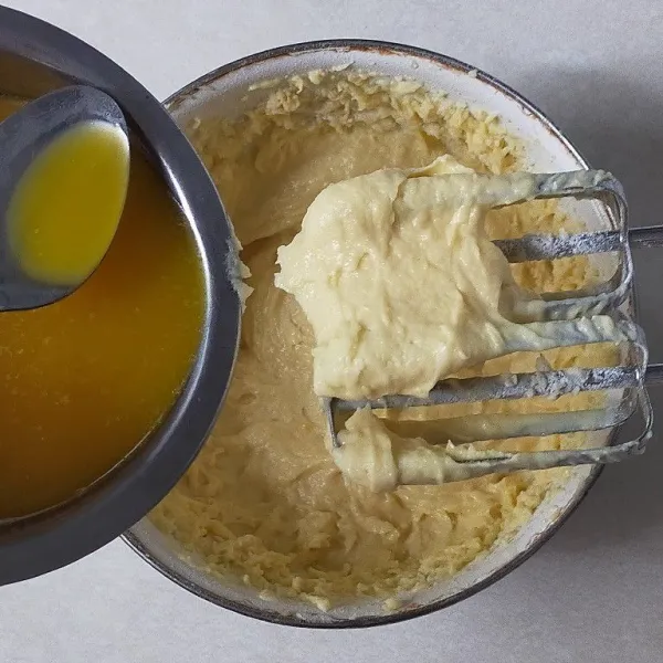 Masukkan tepung terigu bergantian dengan mentega cair.