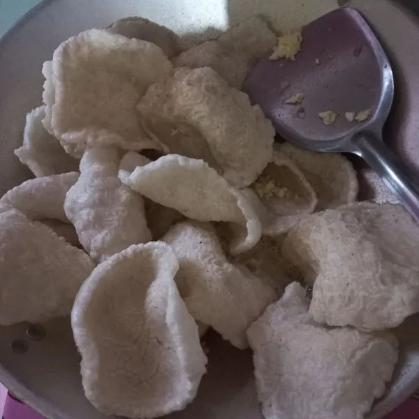 Masukan kerupuk, jika wajan tidak muat, aduk perlahan agar kerupuk mengecil, sambil dimasukkan sisa kerupuk lainnya aduk hingga semuanya menjadi lembut.