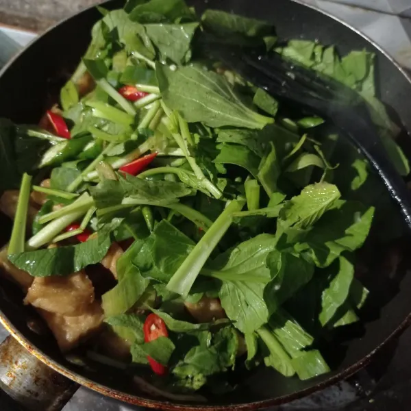 Lalu masukan caisim, daun bawang, dan cabe. Setelah itu, aduk hingga rata.