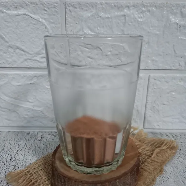 Tuang bubuk minuman coklat ke dalam gelas saji.