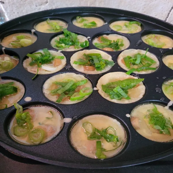 Masukkan adonan kedalam cetakan takoyaki hingga penuh, kemudian tambahkan daun bawang