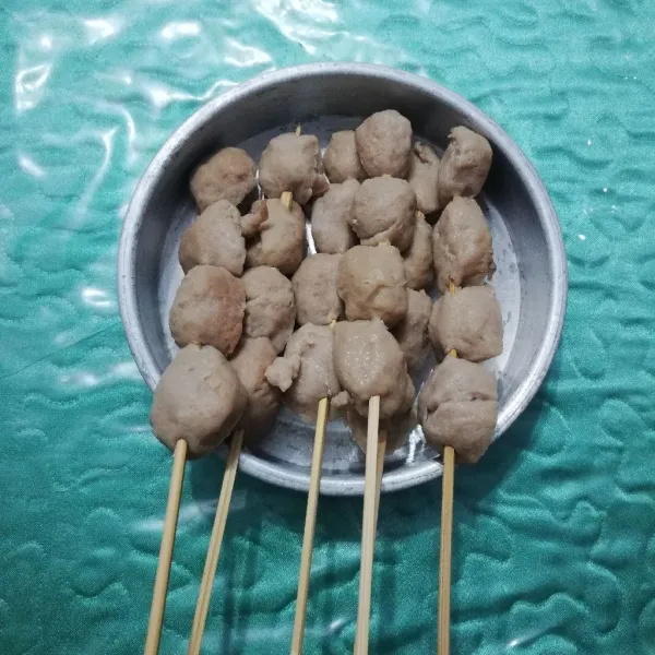 Potong bakso menjadi 2 bagian kemudian tusuk dengan tusuk sate.