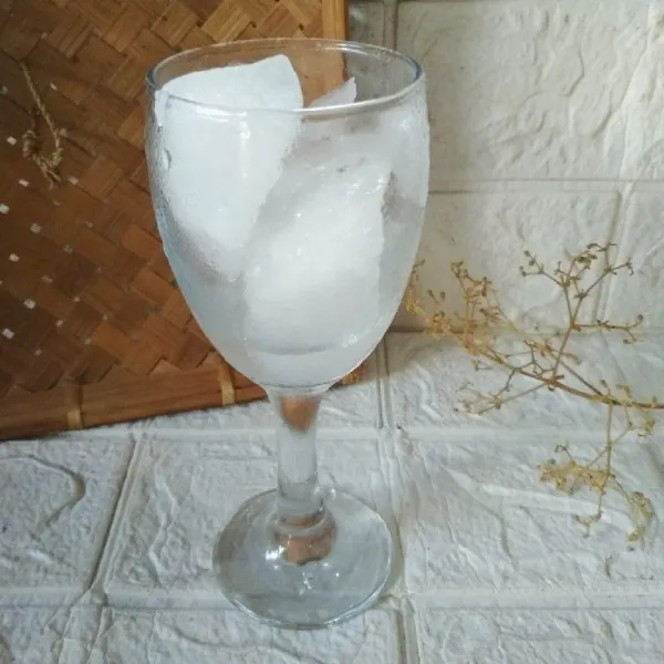 Tuang es batu dalam gelas saji.