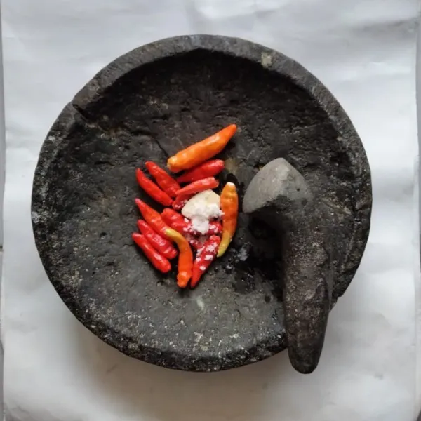 Siapkan cobek, masukkan cabai rawit merah, bawang putih,garam, kaldu jamur dan gula pasir