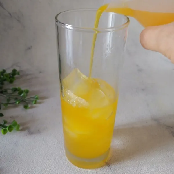 Tuang minuman rasa jeruk sampai 1/2 gelas, tambahkan gula.