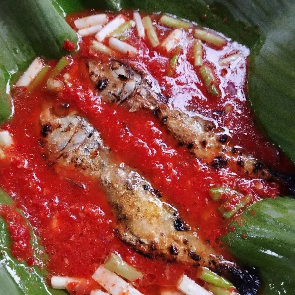 Alasi wajan dengan daun pisang, tuang air, bumbu halus, ikan dan daun bawang.