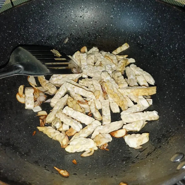 Masukkan tempe dan aduk rata, lalu tuang air.