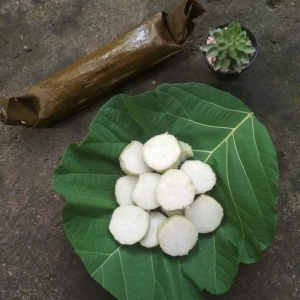 Siapkan piring saji, alasi dengan daun jati, tata irisan lontong.
