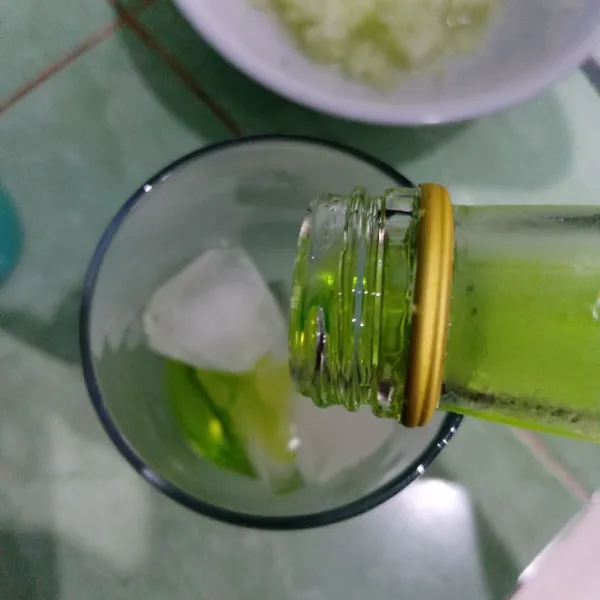 Masukkan es batu dalam gelas lalu tuang sirup melon.