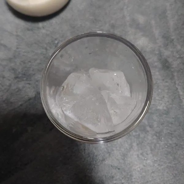 Masukkan es batu di dasar gelas.