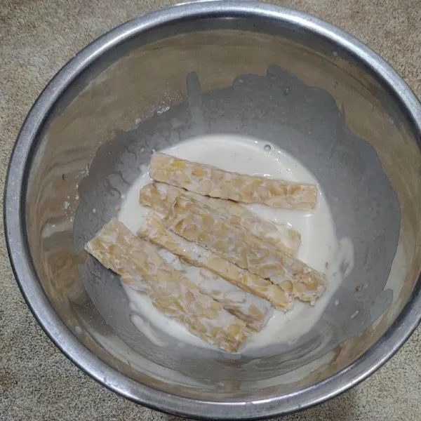 Masukkan potongan tempe ke dalam larutan tepung.