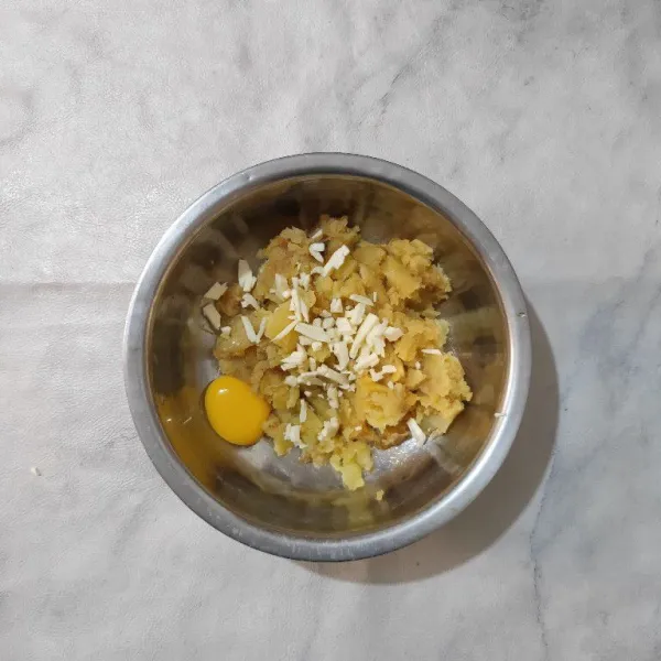 Pindahkan kentang yang sudah dihaluskan ke dalam wadah, lalu tambahkan kuning telur dan keju cincang.
