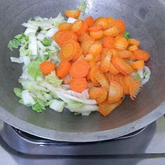 Masukkan wortel dan caisim, air kemudian aduk.