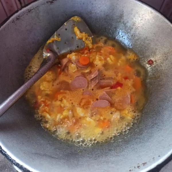 Selanjutnya masukkan air, wortel dan sosis, masak hingga mendidih. Bumbui dengan garam, gula dan kaldu bubuk, aduk rata.