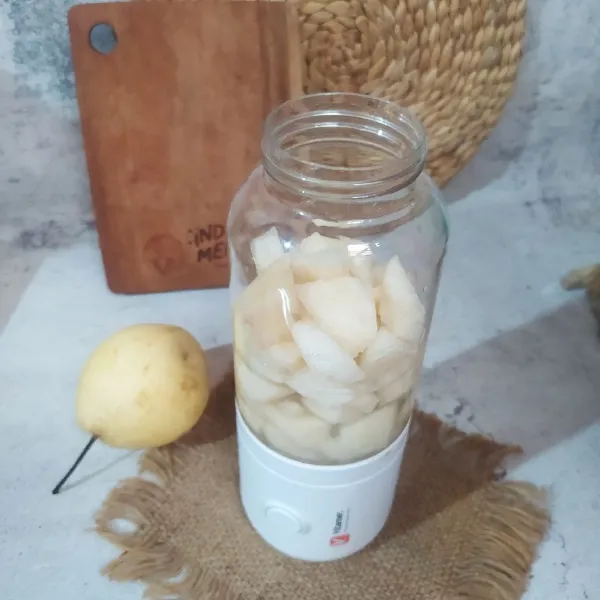 Potong-potong buah pear, masukkan ke dalam blender. Tuang air dan beri es batu.