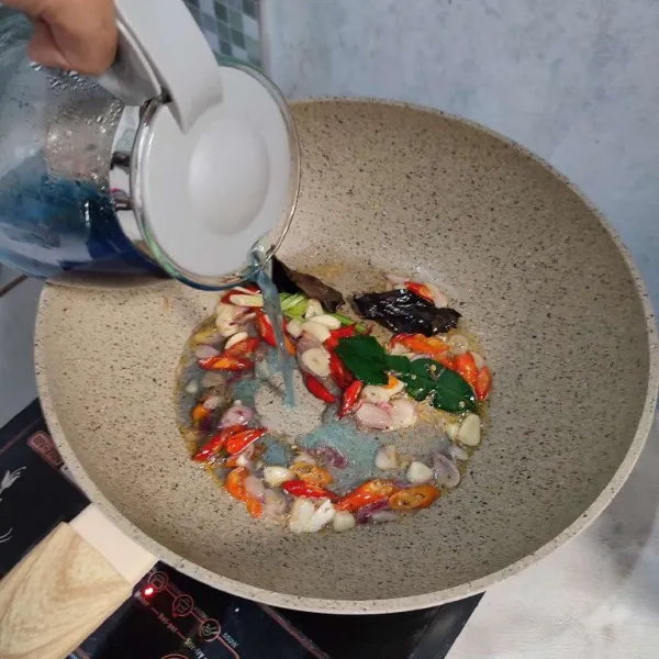 Kemudian masukkan air telang, kurangi takaran air dari memasak nasi biasa agar nasi tidak lembek. Biarkan mendidih. Masukkan juga 2 atau 3 kuntum bunga telang utuh ke dalamnya jika masih punya stok.
