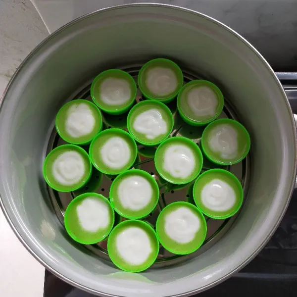 Tuang adonan hijau 3/4 cup, lalu tuang adonan santan di tengah cup sampai cup penuh, kemudian kukus selama 30 menit.