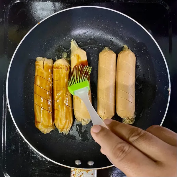 Panaskan teflon dengan mentega/margarin, lalu panggang sosis dan olesi dengan saus.