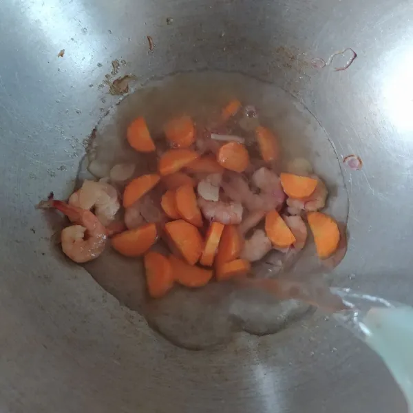 Masukkan wortel dan tuangkan air, aduk rata. Masak hingga wortel agak empuk.