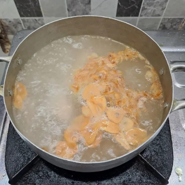 Rebus air kaldu sampai mendidih. Masukkan bawang merah goreng dan bawang putih goreng.