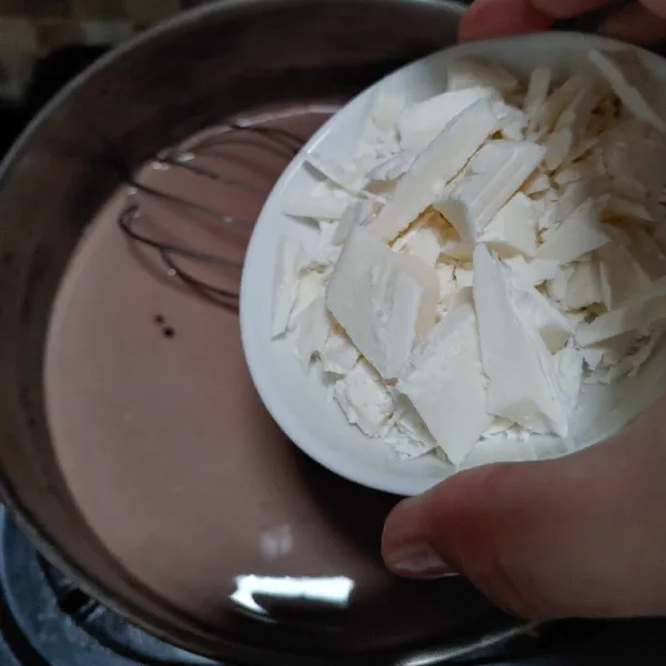Setelah susu cukup panas, masukkan cokelat putih. BIsa diganti pakai dark cokelat.