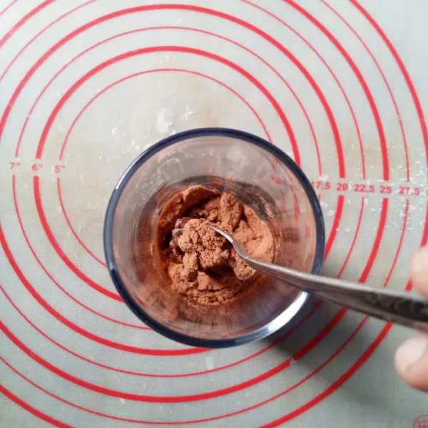 Dalam gelas saji ukuran 500 ml, masukkan bubuk cokelat dan kental manis cokelat, aduk rata sampai menjadi pasta.