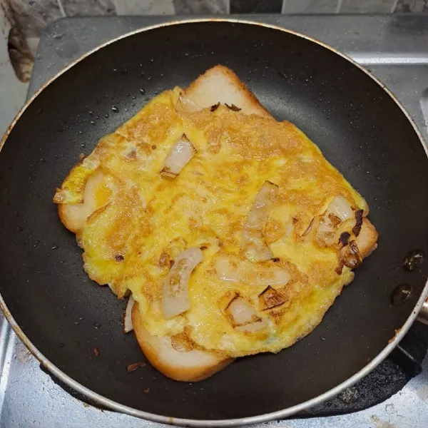 Balik perlahan telur, panggang sampai roti tawar kecokelatan. Angkat dan letakkan di atas piring.