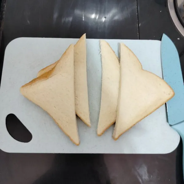 Potong roti tawar menjadi 2 bagian bentuk segitiga.
