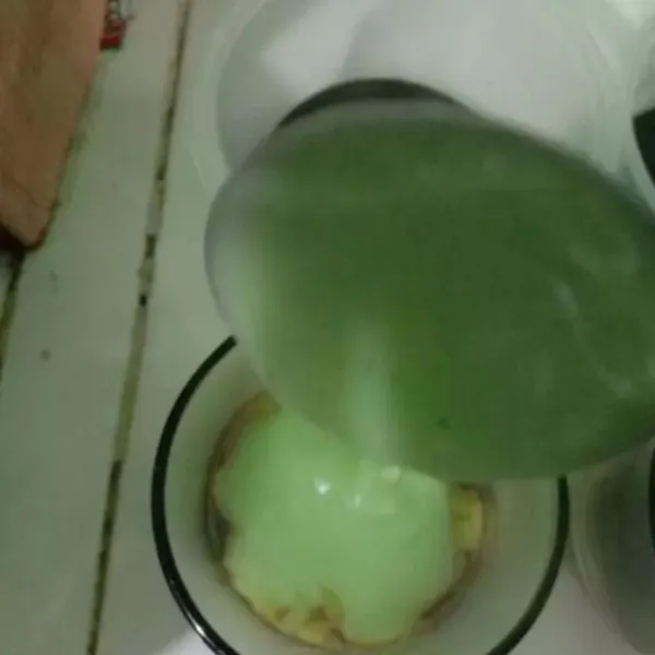Tuang panas-panas adonan hijau ke dalam gelas plastik yang didalamnya sudah ada kinca gula merahnya, sisihkan.