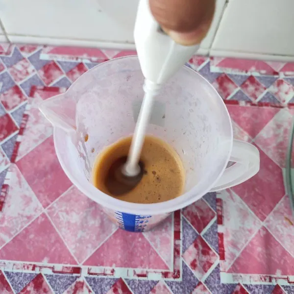 Seduh kopi bubuk dengan 50 ml air mendidih, kemudian aduk menggunakan milk frother hingga berbusa.