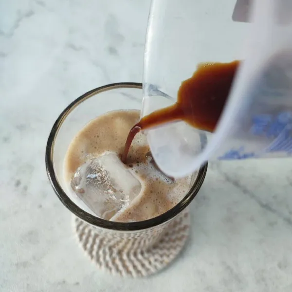 Tuang seduhan kopi dan tambahkan busa kopi di atasnya. Aduk rata dan sajikan selagi dingin.