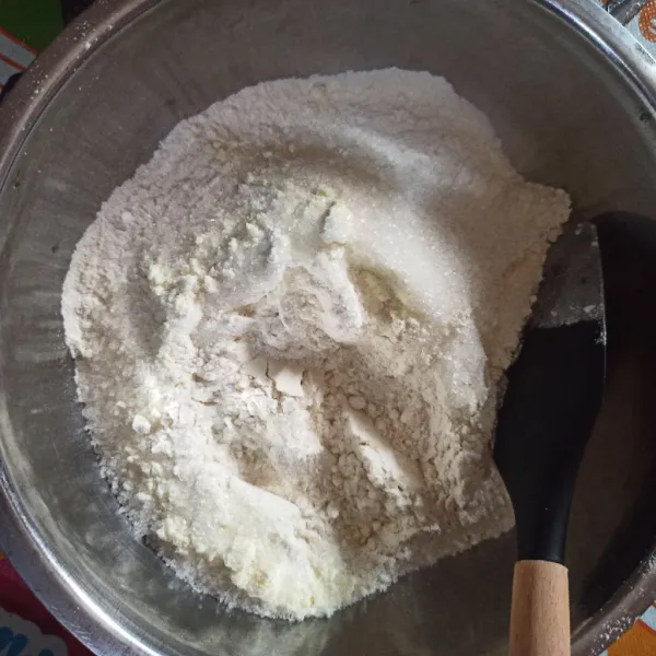 Ayak tepung terigu dan baking powder. Lalu tambahkan susu bubuk, gula pasir, ragi instan. Aduk rata.