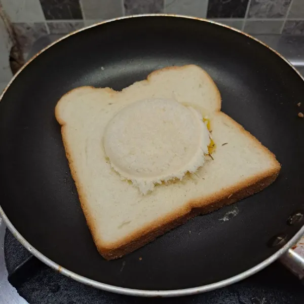 Tutup lubang dengan sisa roti tawar. Biarkan sampai bagian bawah roti kecokelatan dan telur berkulit.