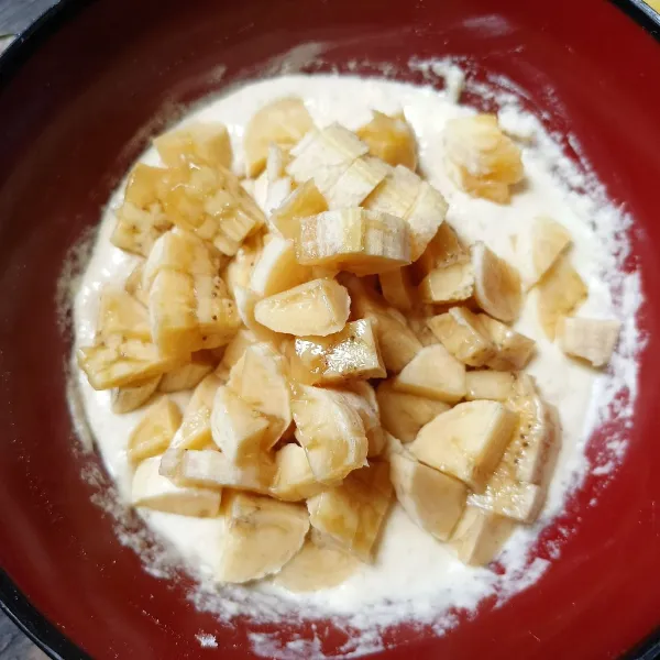 Kupas pisang dan potong-potong kecil, lalu masukkan ke dalam adonan tepung dan aduk rata.