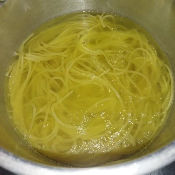 Masak air hingga mendidih, lalu masukkan minyak goreng dan spaghetti, lalu rebus hingga matang sekitar 12 menit, angkat lalu tiriskan.