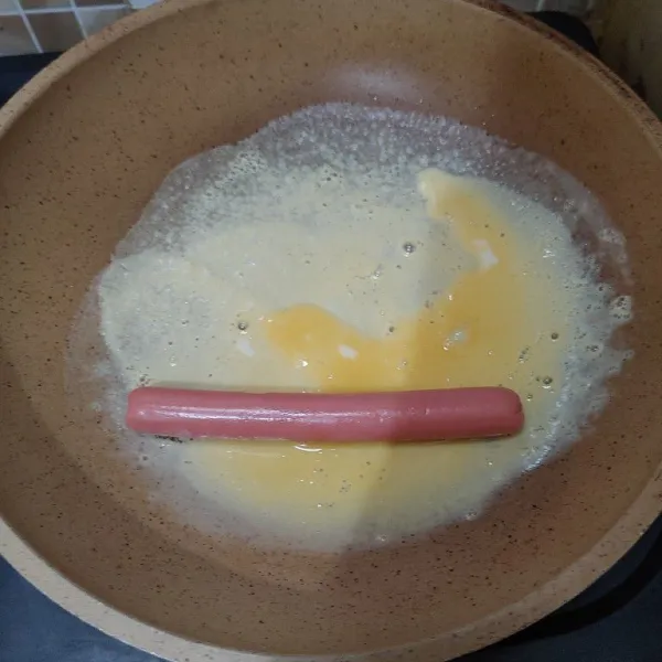 Panaskan teflon, beri sedikit minyak, lalu buat dadar tipis dan masukkan sosis, perlahan gulung. Lalu tuang sisa kocokan telur.
