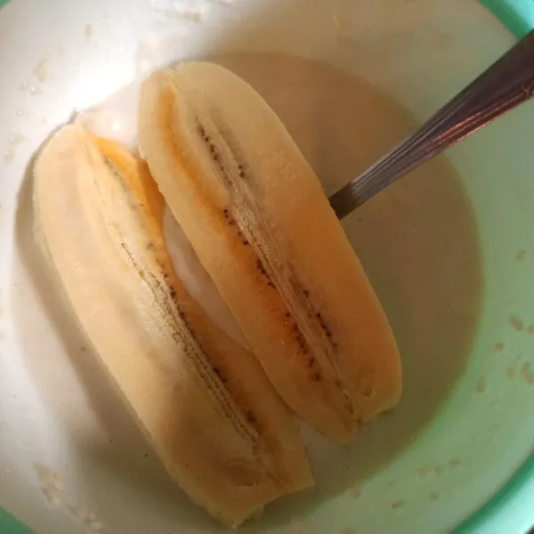 Masukkan pisang yang sudah dibelah menjadi dua ke dalam adonan tepung.
