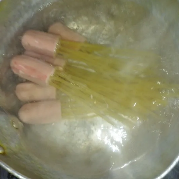 Lalu tusukkan spaghetti ke atas sosis, tusuk spaghetti satu demi satu sebanyak 10 buah spaghetti, lalu rebus spaghetti dalam air yang sudah mendidih.