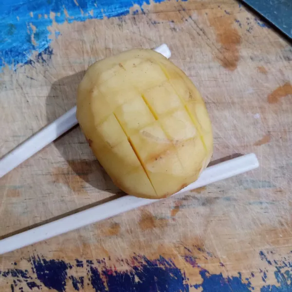 Letakkan sumpit di sisi kanan kiri, lalu iris kentang seperti pada gambar.
