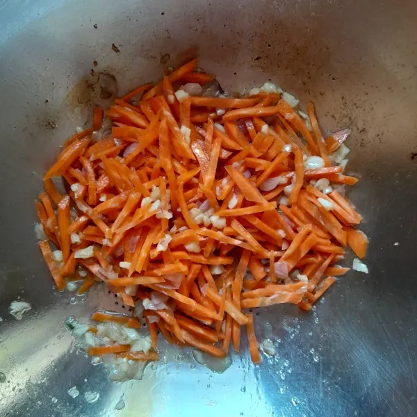 Masukkan potongan wortel, aduk rata. Tumis hingga wortel layu dan setengah matang.