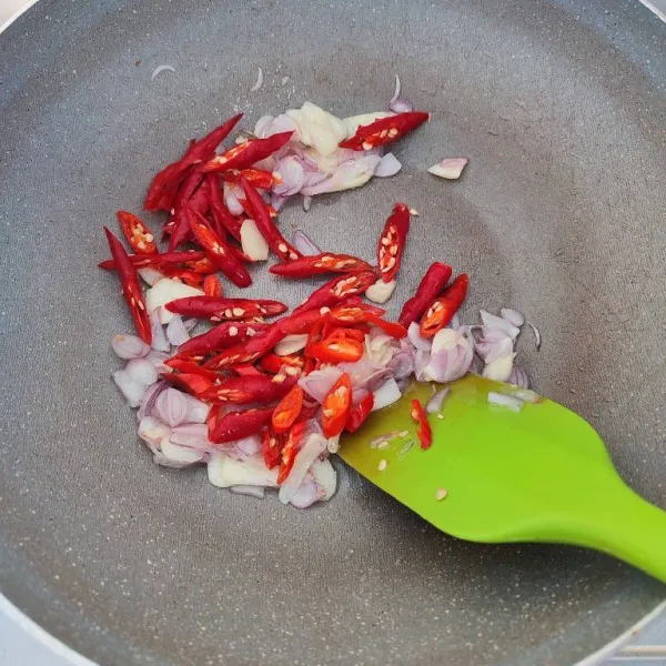 Tambahkan irisan cabe merah keriting dan cabe rawit, tumis kembali hingga layu.