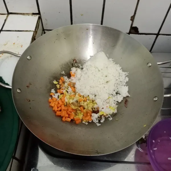 Masukkan wortel dan nasi. Aduk rata. Masak hingga wortel sedikit layu.