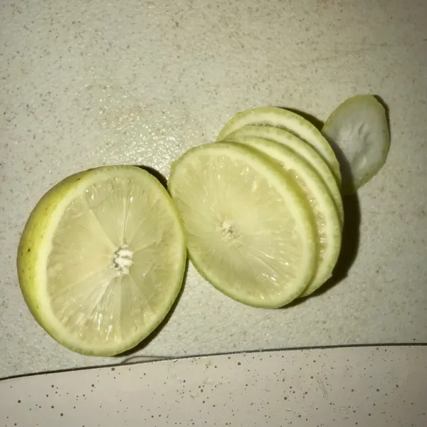 Potong dua bagian lemon, satu bagian iris tipis-tipis