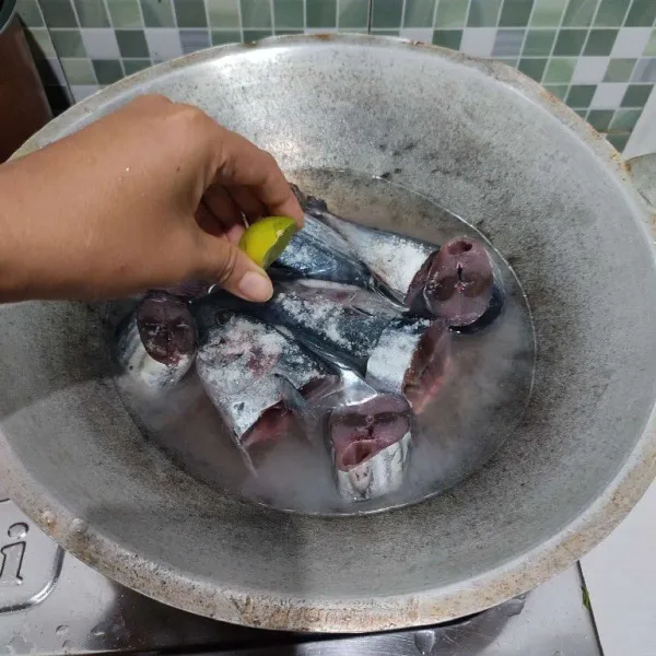 Masukkan ikan tongkol yang sudah dicuci bersih ke dalam wajan, beri air, garam serta perasan jeruk nipis.