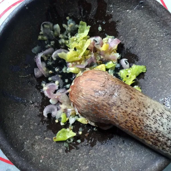 Haluskan bawang putih dengan garam dan penyedap rasa. Ulek kasar cabe rawit dan bawang merah.