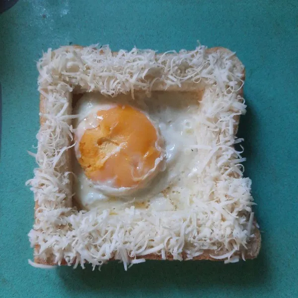 Olesi roti dengan mayonaise susun telur dan roti taburi dengan keju siap dihias.