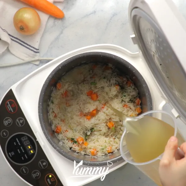 Tuangkan air kaldu, tutup rice cooker dan masak hingga matang.