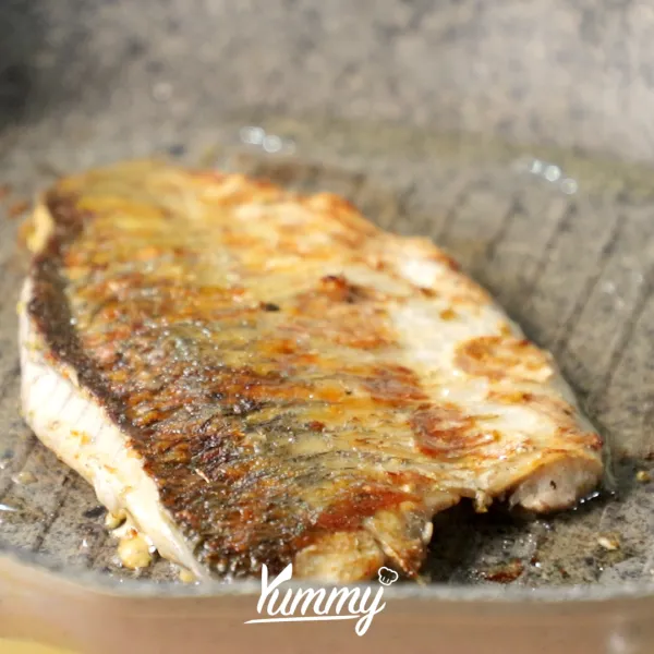 Panaskan grill pan, kemudian beri sedikit minyak dan panggang ikan dengan posisi kulit di bawah selama 7 menit. Balik ikan secara perlahan, dan masak kembali selama 7 menit, lalu angkat dan sisihkan.